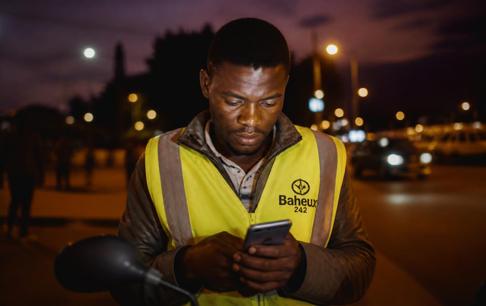Conducteur de moto-taxi enregistrant son versement sur son téléphone à Kinshasa